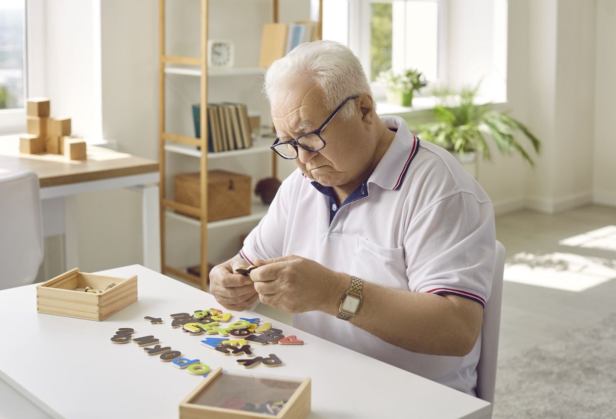 Senior adult working on a large-piece jigsaw puzzle in a calm, clutter-free apartment—promoting mental engagement in a dementia-friendly space.