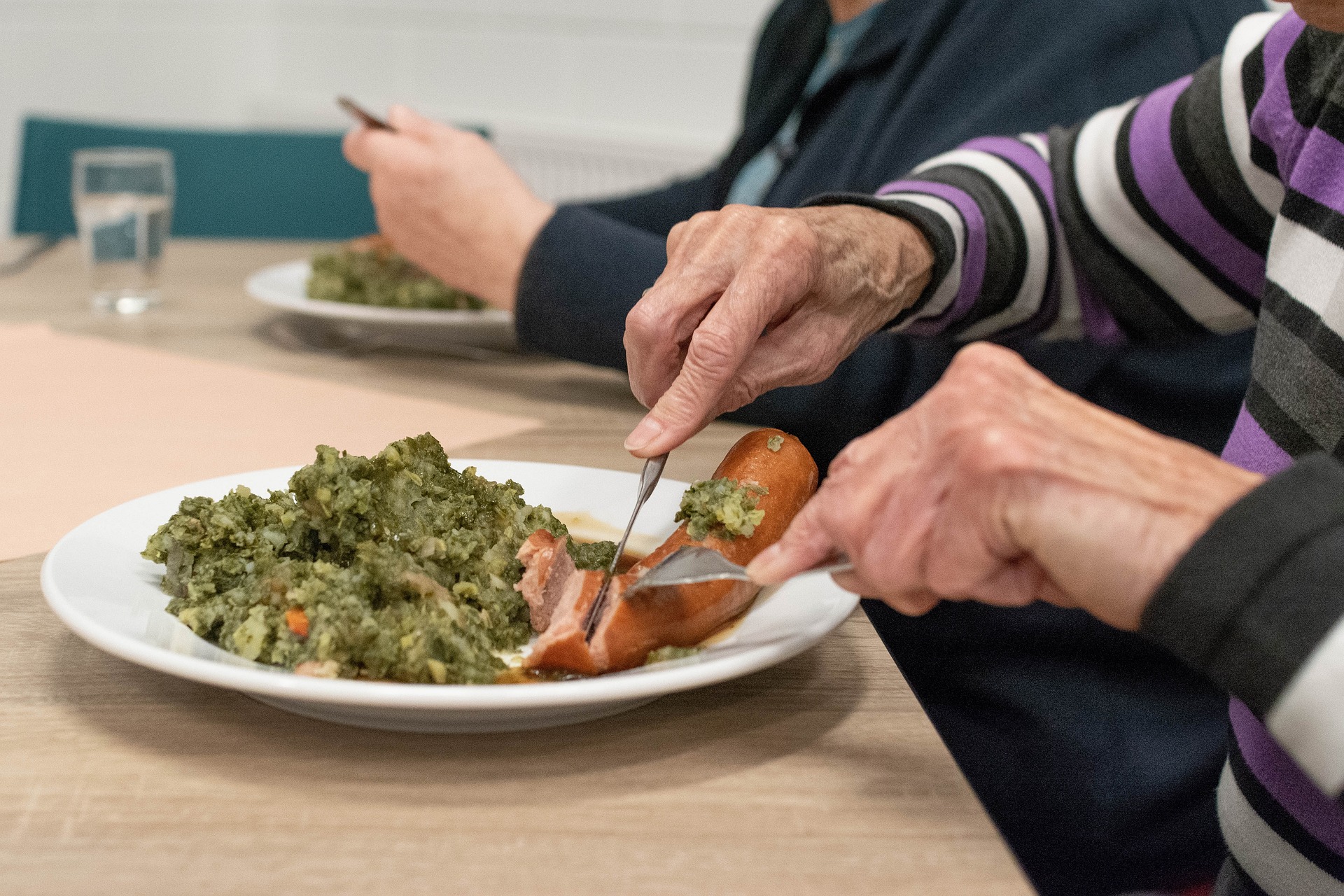 image of a plate of food and hands cutting food with knife and fork this image is decorative and represents meal services