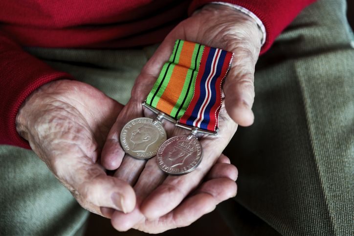 the purpose of this image is to show the aging hands of a male Veteran holding his war medals, indicating his service to his country