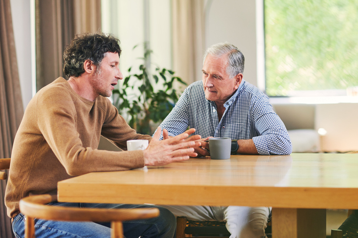 image of a younger man having coffee and talking with an aging adult male