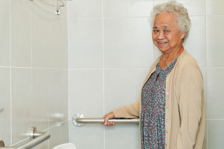 senior adult woman holding a grab bar in the bathroom to avoid falling