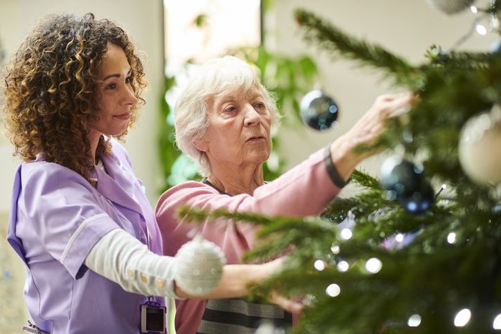 senior adult and younger woman decorating a Christmas tree creating warmth and connection during the holiday season