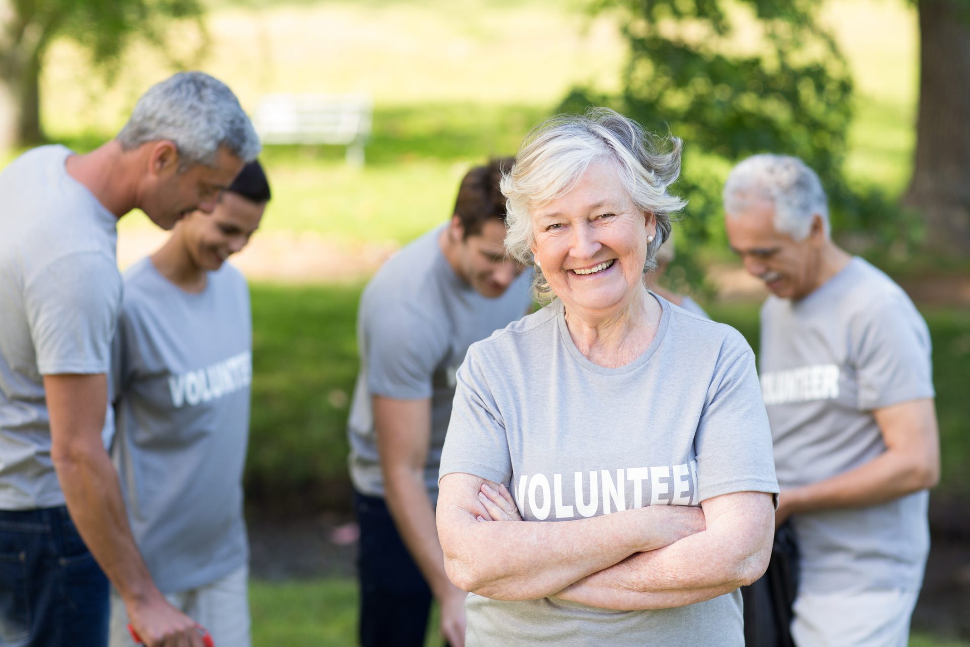 Happy volunteer senior adult woman smiling at camera on a sunny day