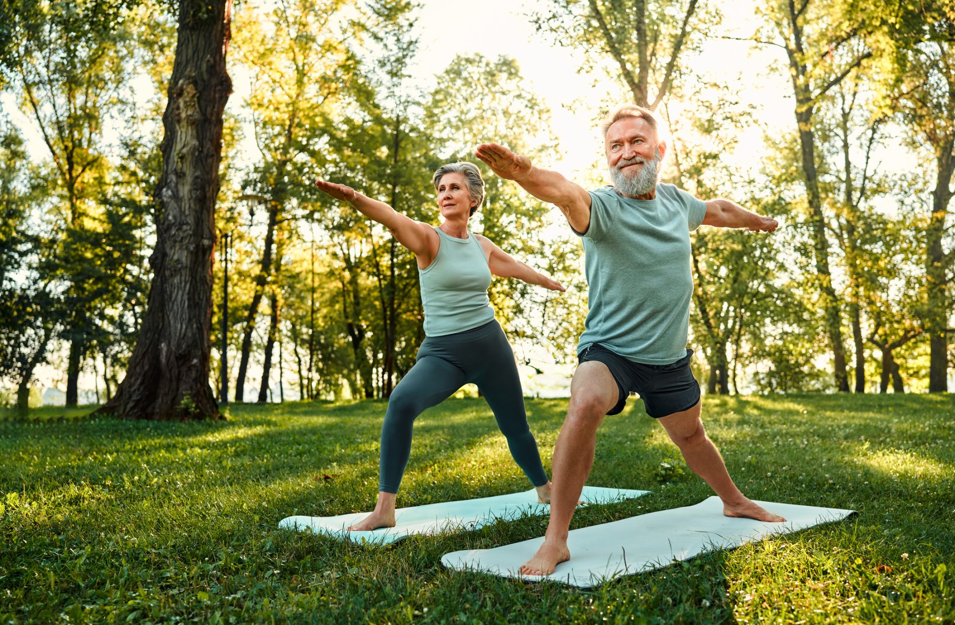 Senior adults standing on rubber mats doing yoga to improve their balance.
