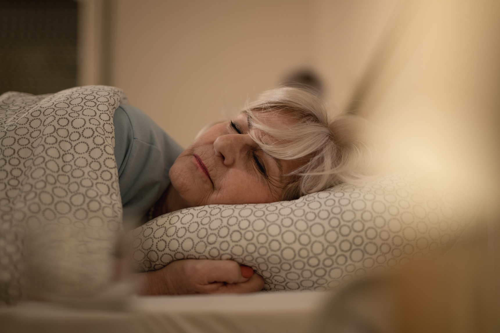 Senior adult woman sleeping on her bed.