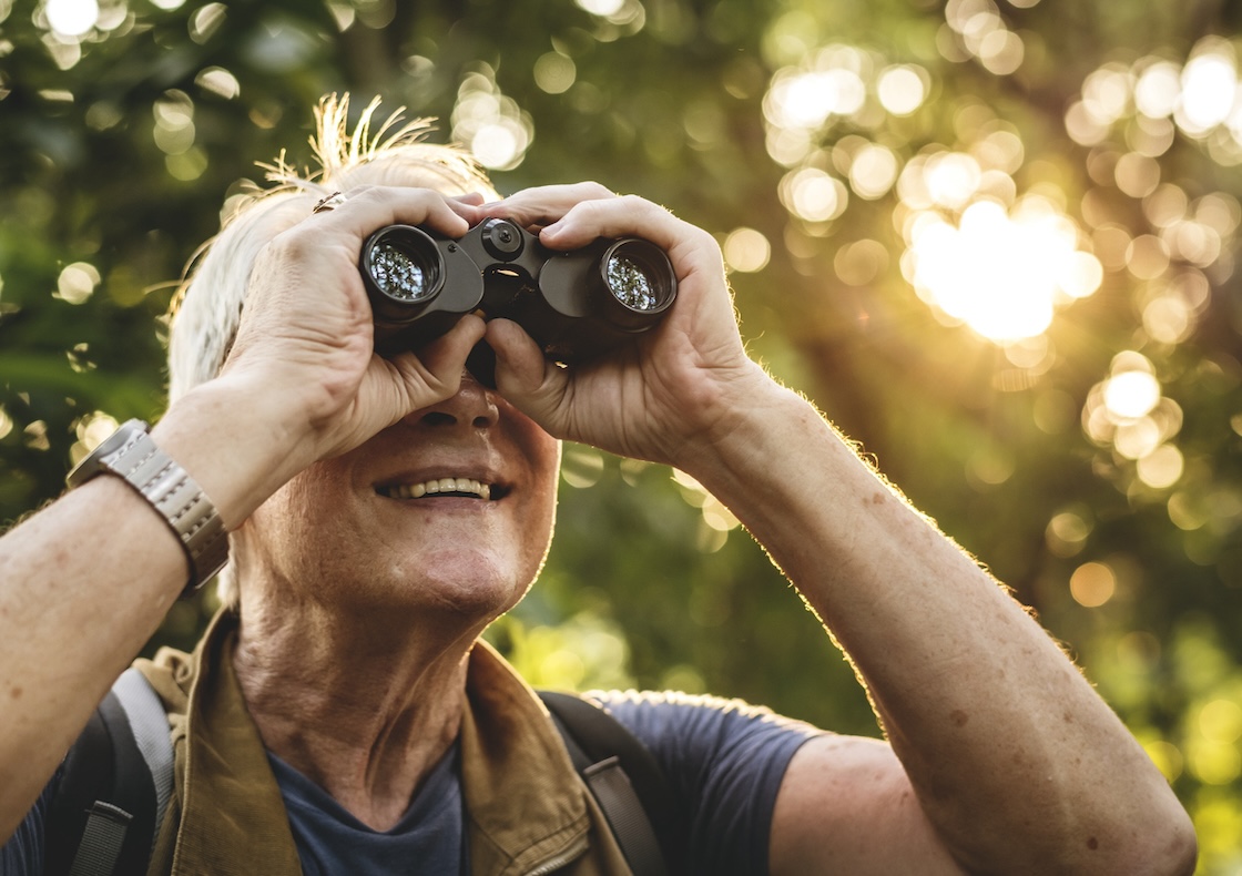 Mature man watching birds through binoculars, in South Knoxville during the fall season.