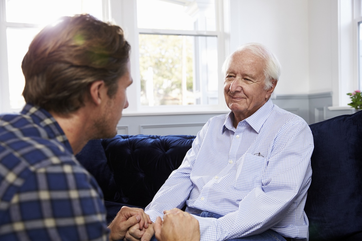 Adult son talking with senior adult at home about safety and living arrangements