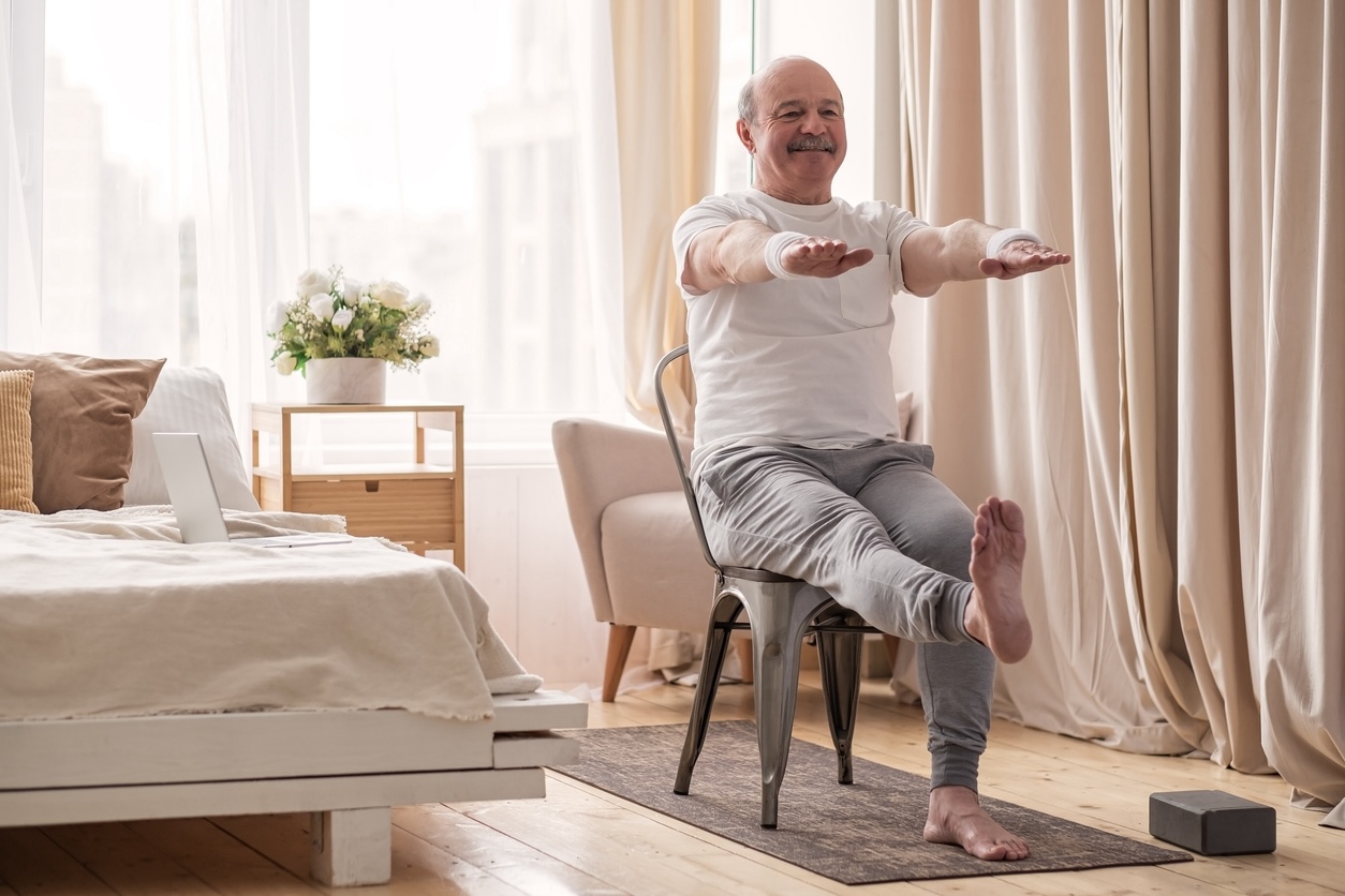 Senior adult practicing balance exercises for seniors with chair support