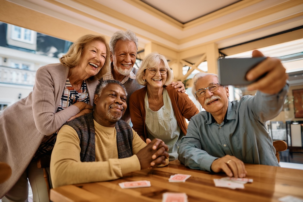 Senior adults laughing and taking a selfie together during a social activity in a senior living community