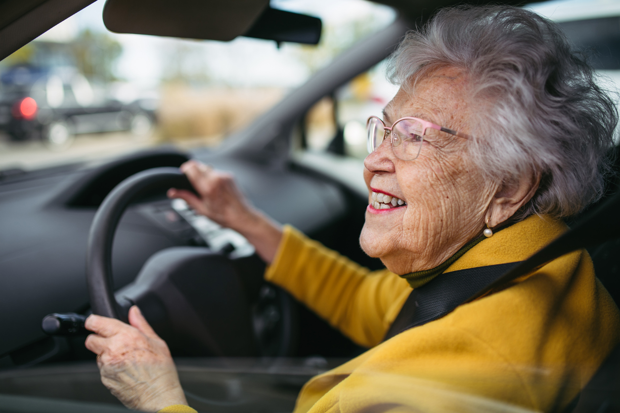 Senior adult woman smiling while driving car