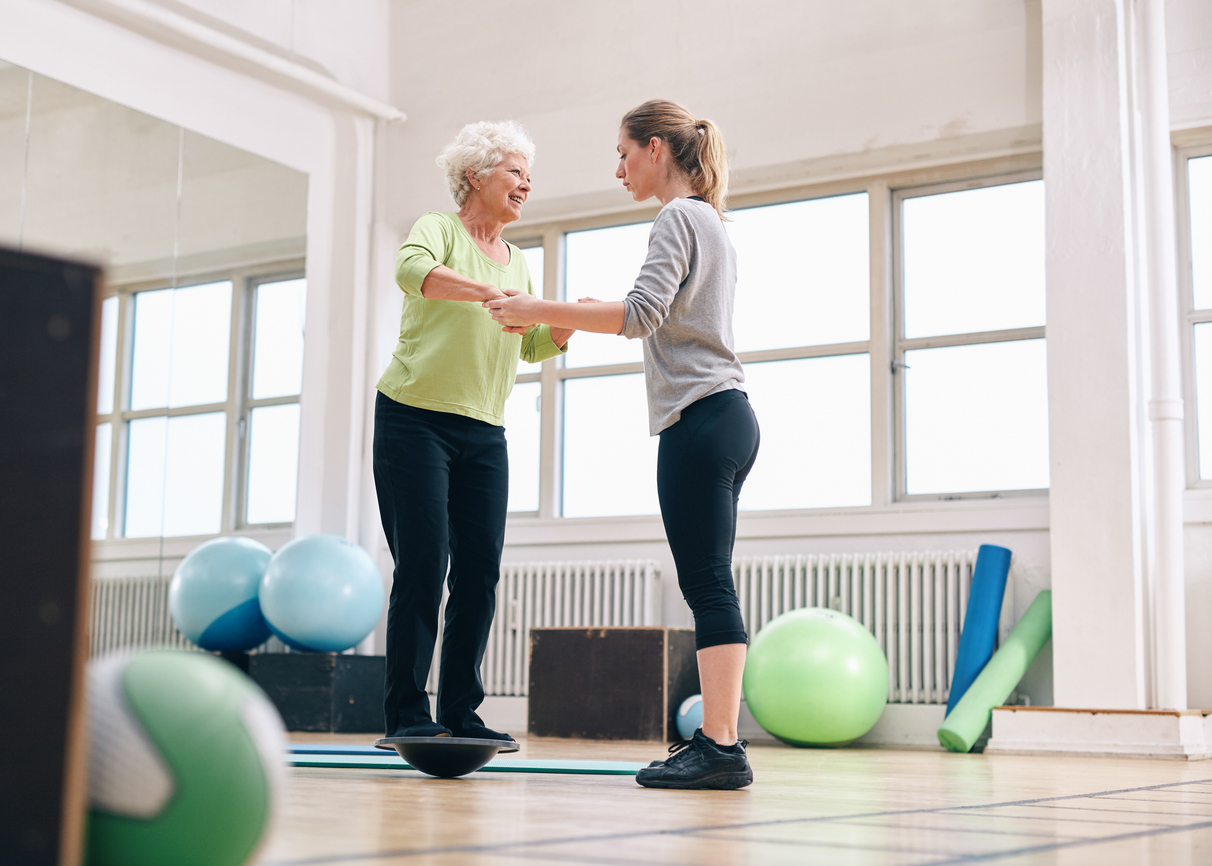 Senior woman practicing balance exercises with a physical therapist