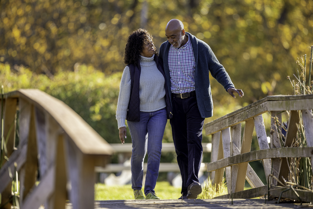 Senior adult couple walking outdoors surrounded by fall foliage